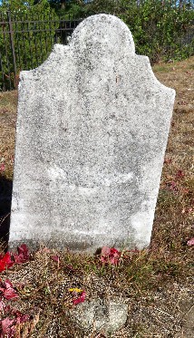 Old marble grave stone set in a grassy area with a concrete round in front