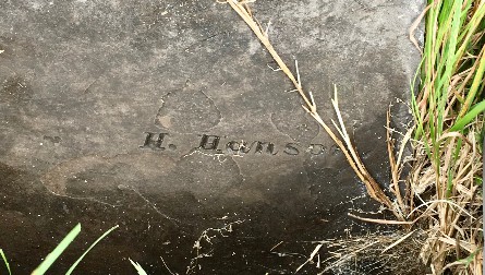 detail of an old slate grave marker carved with H. Hanson