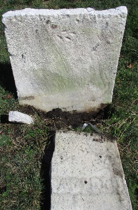 photo of old marble grave marker set in the ground, but a shard is also in the ground, and the top is laying in the grass in front