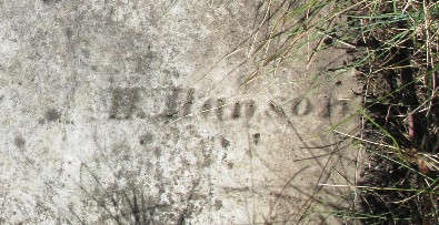 detail of old marble gravestone carved with H. Hanson buried in the sod