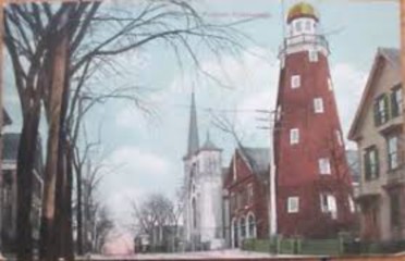 old postcard of the Portland Observatory set in its neighborhood with buildings and trees around it