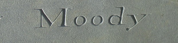 detail of an old slate gravestone carved with the name Moody