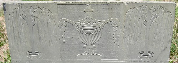 Detail of a slate grave stone with a carving of an urn and a willow on each side