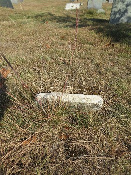 an old broken marble gravestone in a grassy graveyard