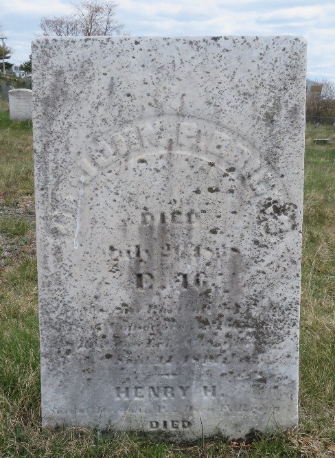 old weathered rectangular white marble gravestone, set in a grassy cemetery, covered with black lichen and carved with a name and inscription for Dr. John P. Briggs